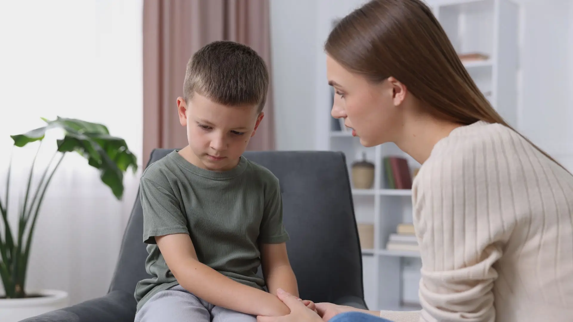 Parent sitting calmly beside an emotionally overwhelmed child during a difficult moment at home